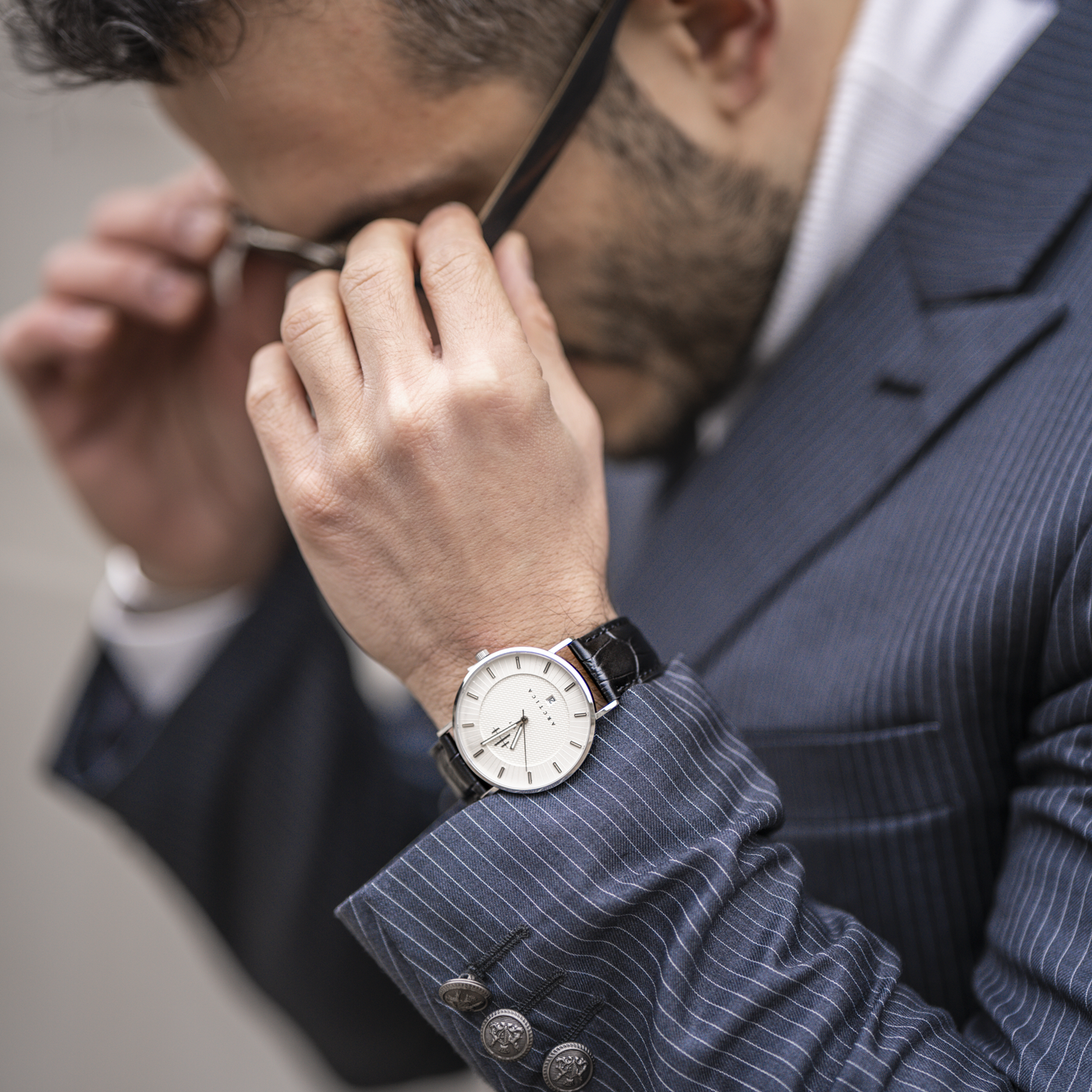 Man with blue suit wearing black and white THT watch.